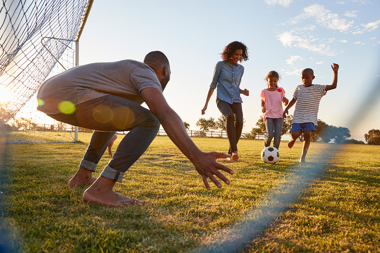 a-boy-kicks-a-football-during-a-game-with-his-family-829627936_5472x3648